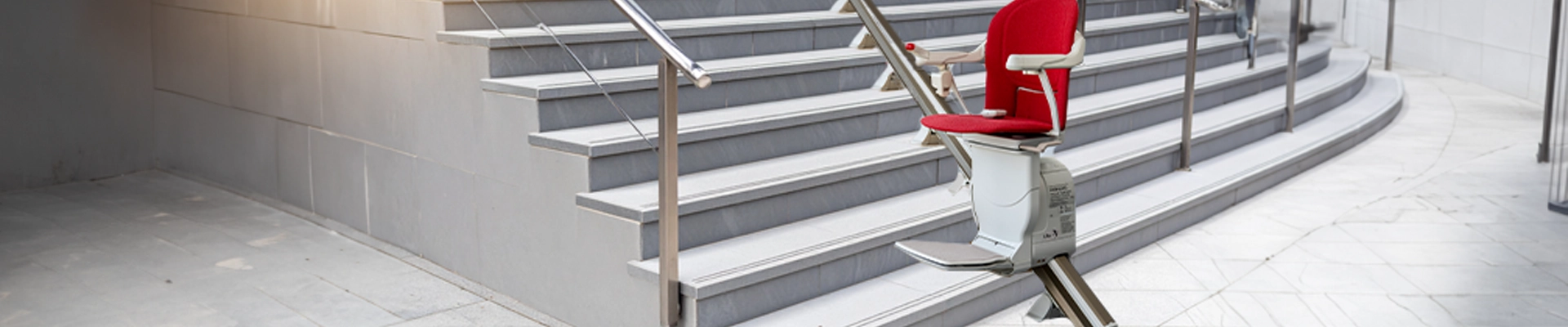 Es ist eine große breite Treppe im Aussenbereich mit Edelstahl Geländer zu sehen. Es sind mehr als 7 Treppenstufen. Mitten in der Treppe befindet sich ein Treppenlift. Es soll ein Symbolbild für Barrierefreiheit darstellen.