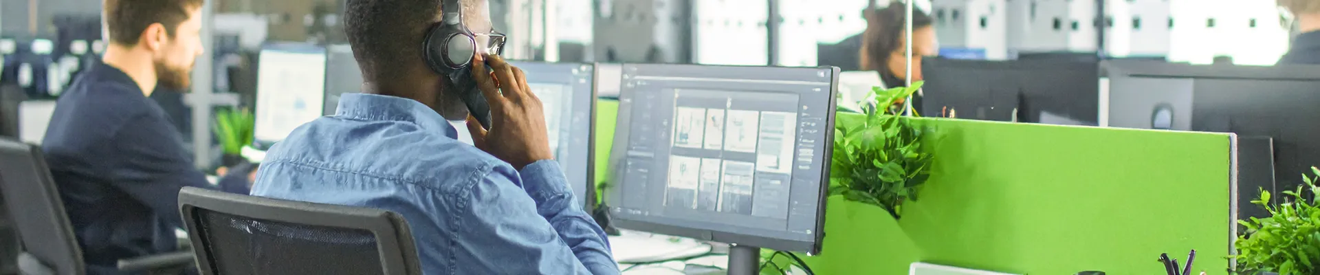 In einem Büro sitzen mehrere Personen und telefonieren. Es ist ein Großraumbüro.