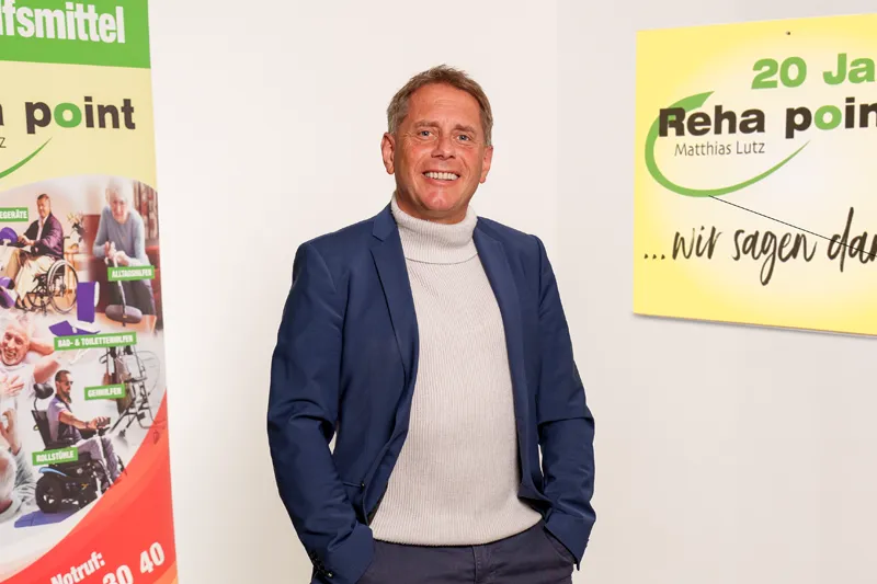 Matthias Lutz im Verkaufsraum bei Reha Point Nürtingen. Links und rechts sind Banner zu sehen mit Werbung von Reha Point